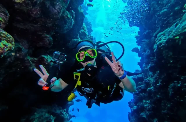 Diver with a camera making a peace sign underwater