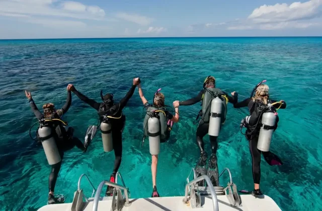 Divers jumping off a boat into the sea, hands raised