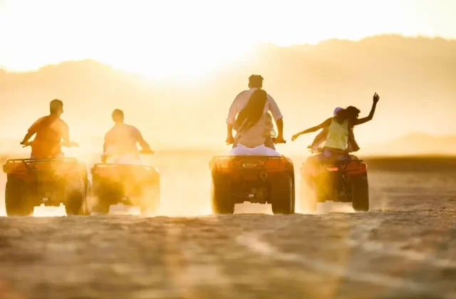 Group of quad bike riders in the desert at sunset