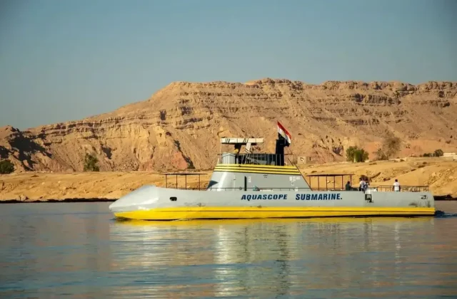 Gelb-weißes Halb-U-Boot an der Wasseroberfläche vor Wüstenhügeln