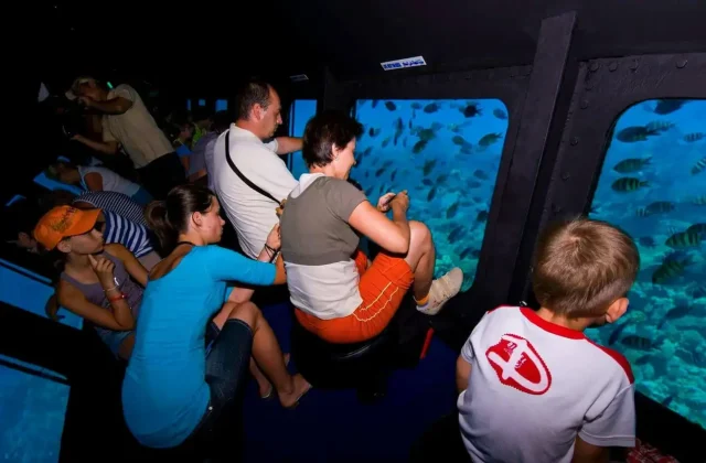 Family watching fish through submarine windows